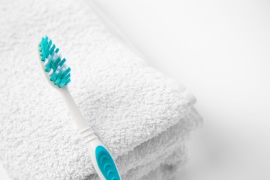 Light blue toothbrush and terry towel on white background, closeup