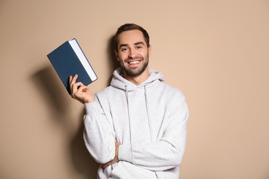 Photo of Young happy man with book on color background