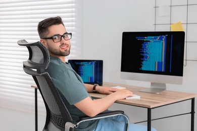 Photo of Happy young programmer working at desk in office