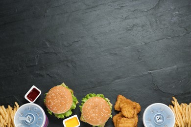 Photo of Flat lay composition with delicious fast food menu on black table. Space for text