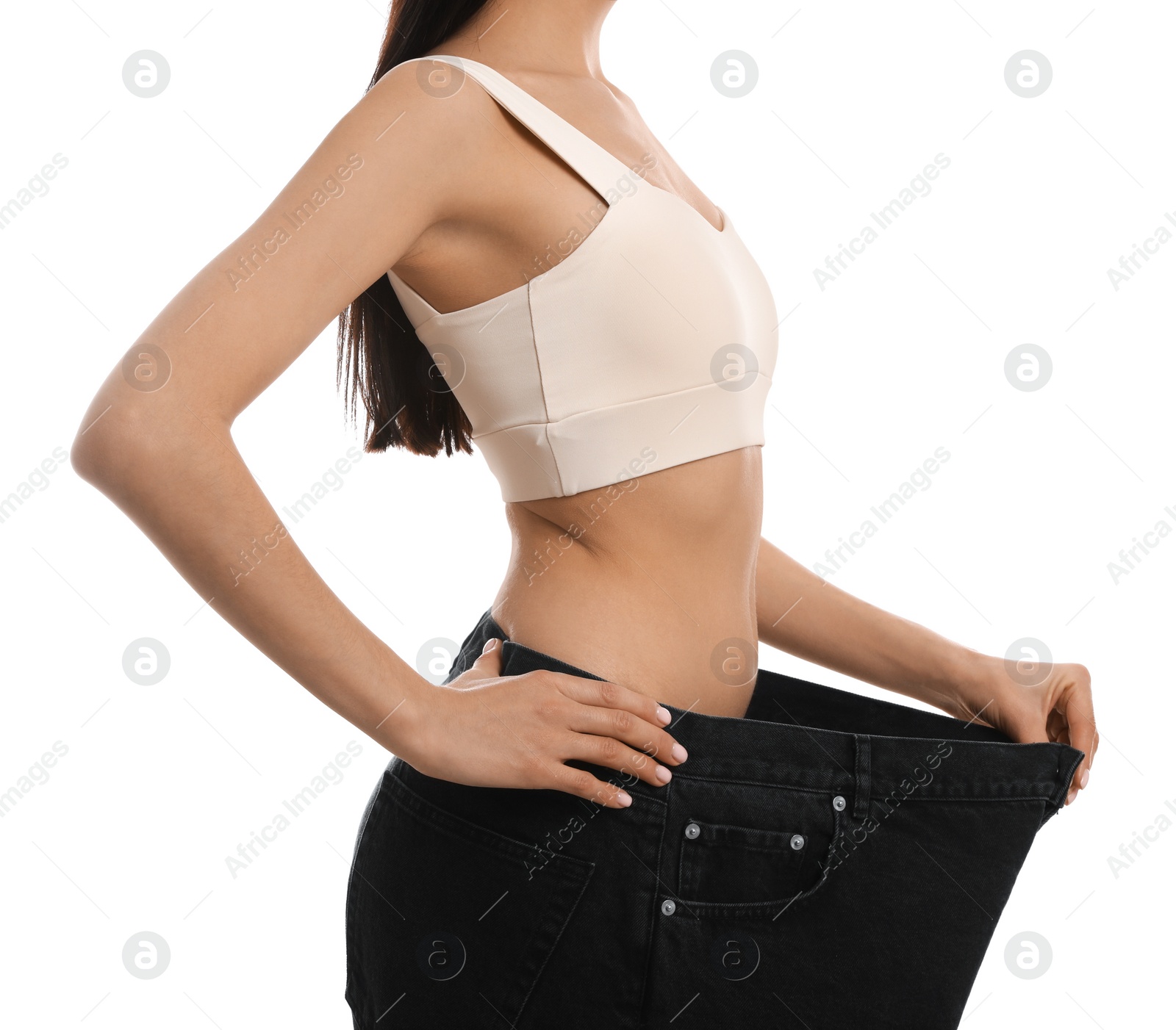 Photo of Young woman wearing big jeans after weight loss on white background, closeup