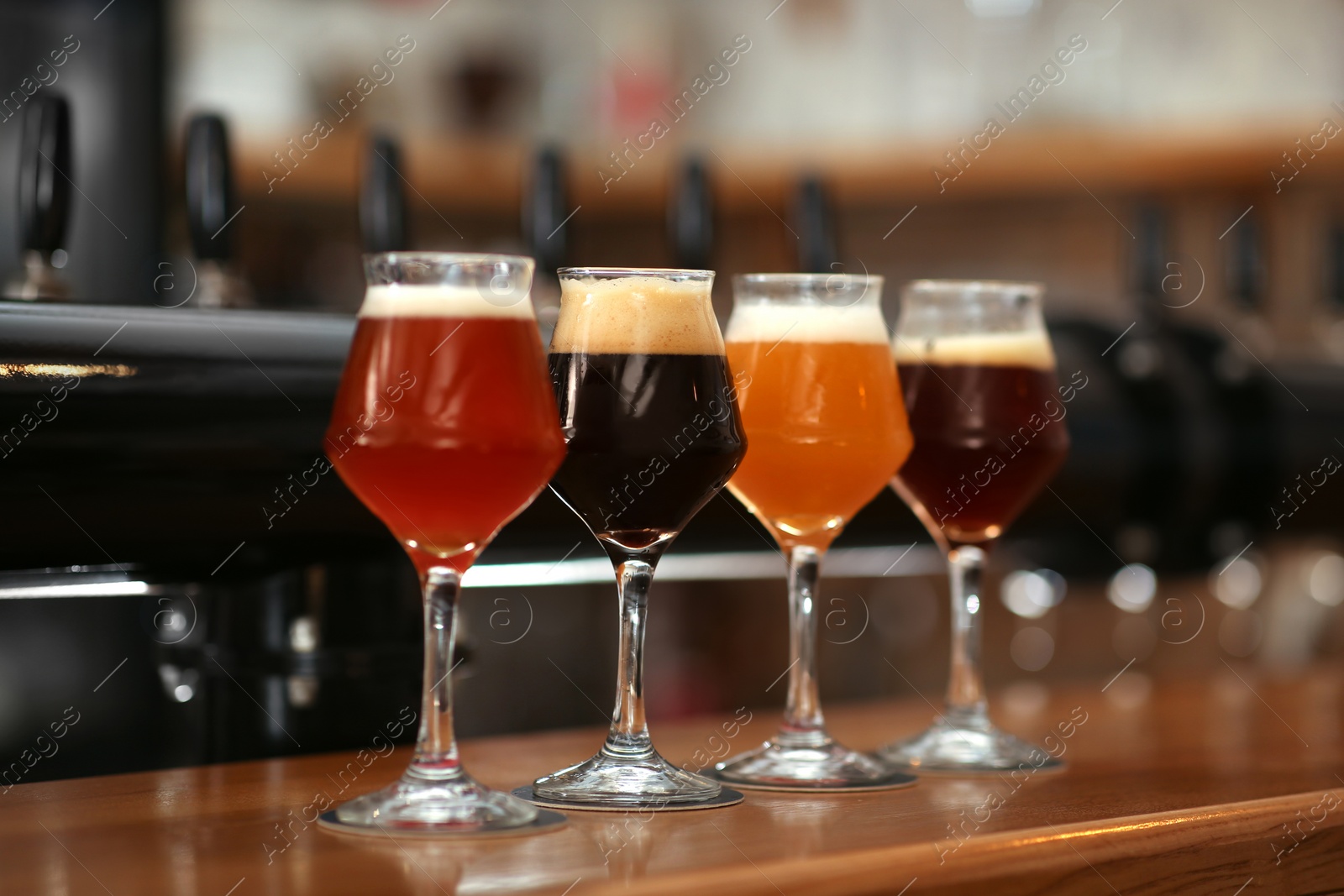 Photo of Different beers in glasses on bar counter