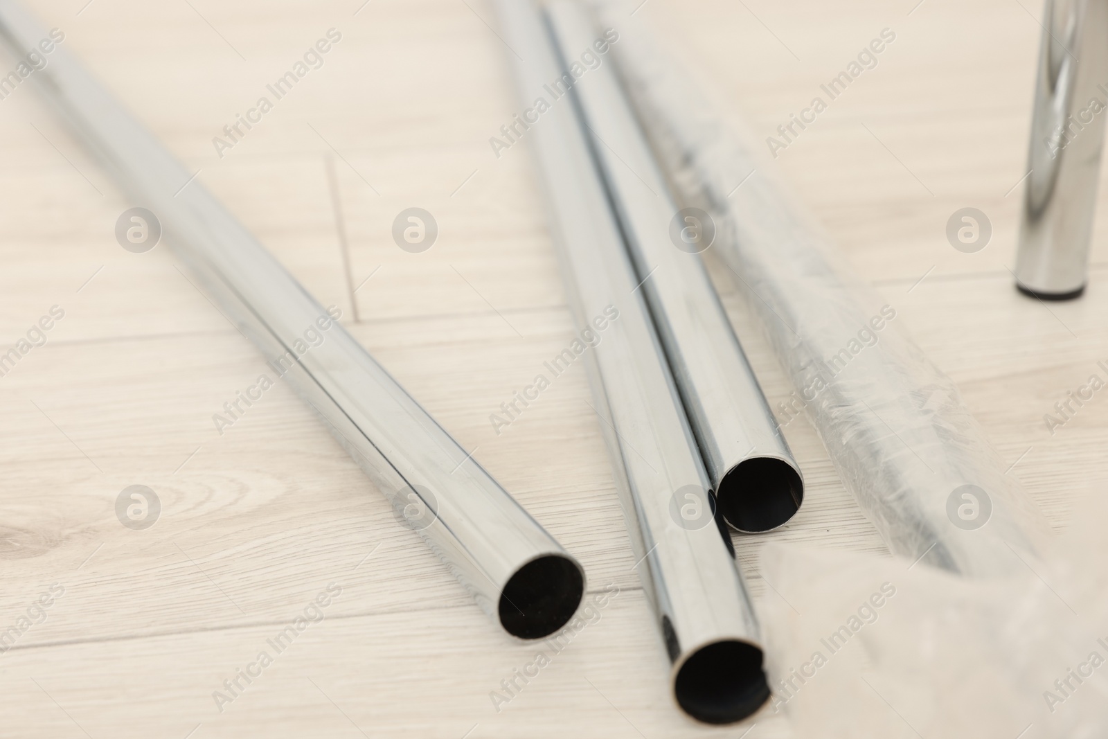 Photo of New modern metal pipes on wooden floor, closeup