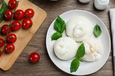 Delicious burrata cheese with basil served on wooden table, flat lay