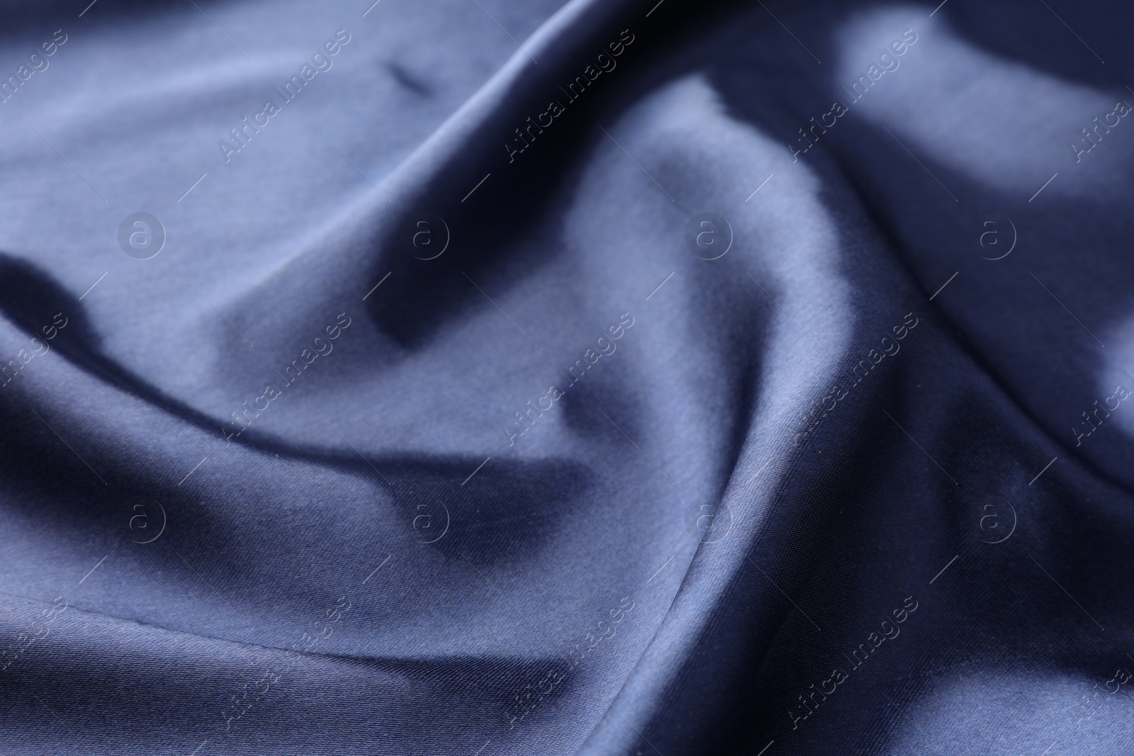 Photo of Crumpled dark blue silk fabric as background, closeup