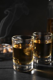 Photo of Alcohol addiction. Whiskey in glasses on black wooden table
