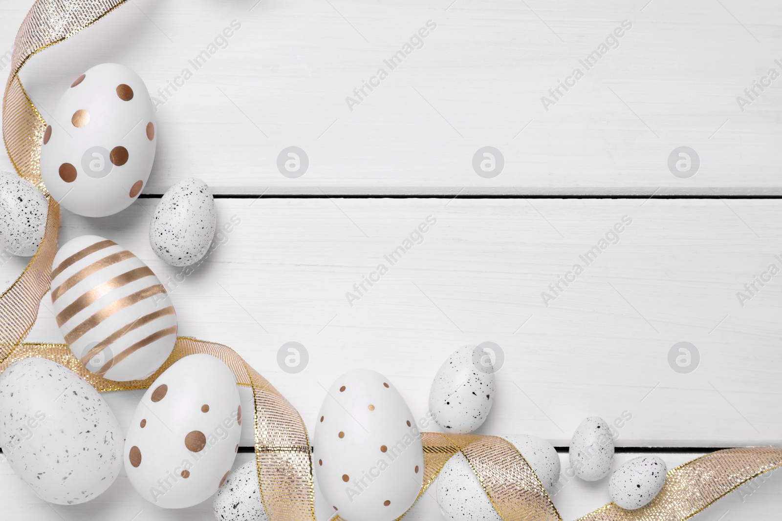 Photo of Flat lay composition with festively decorated Easter eggs on white wooden table. Space for text