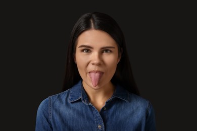 Photo of Personality concept. Emotional woman showing tongue on black background