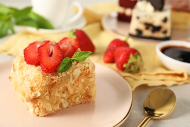 Photo of Piece of delicious Napoleon cake with fresh strawberries on light grey table, closeup. Space for text