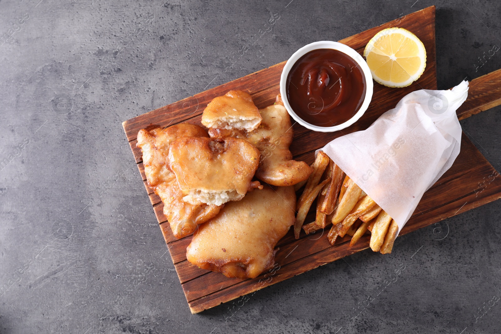 Photo of Tasty fish, chips and sauce on grey table, top view. Space for text