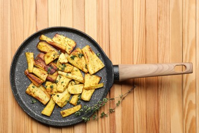Delicious parsnips with thyme in frying pan on wooden table, top view