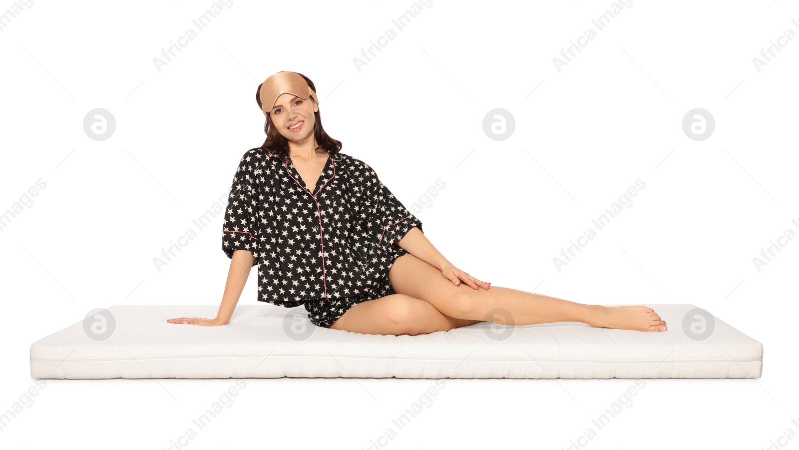 Photo of Woman in sleep mask sitting on soft mattress against beige background