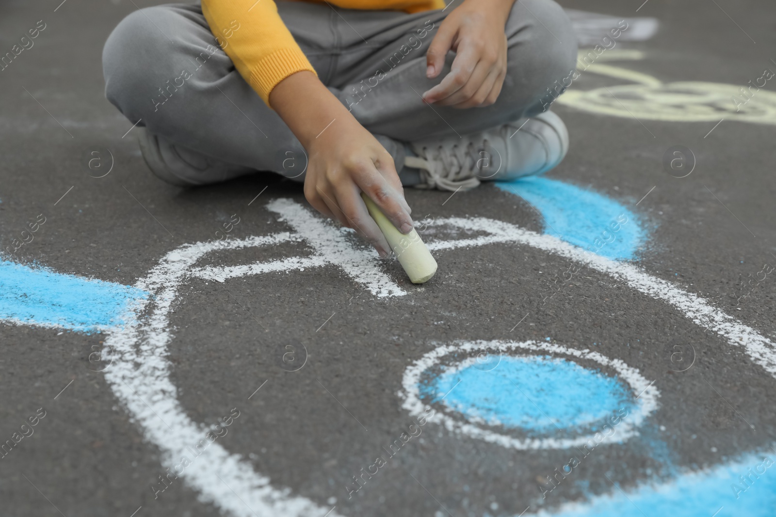 Photo of Child drawing rocket with chalk on asphalt, closeup