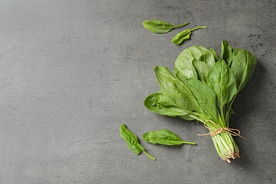 Bunch of fresh green healthy spinach on grey table, top view. Space for text