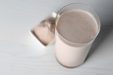 Photo of Glass with protein shake on white table, closeup. Space for text