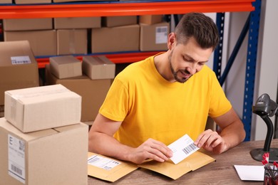 Photo of Post office worker sticking barcode on parcel at counter indoors