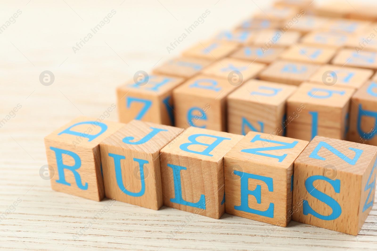 Photo of Word Rules made of cubes with letters on light wooden table