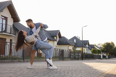 Photo of Happy couple dancing near house on city street. Space for text
