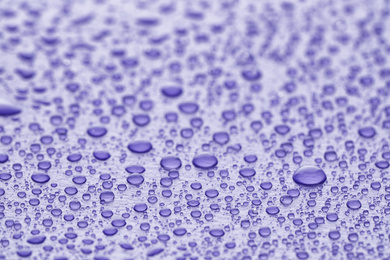 Photo of Water drops on lilac background, closeup view