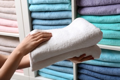 Photo of Woman holding towels near shelf, closeup view