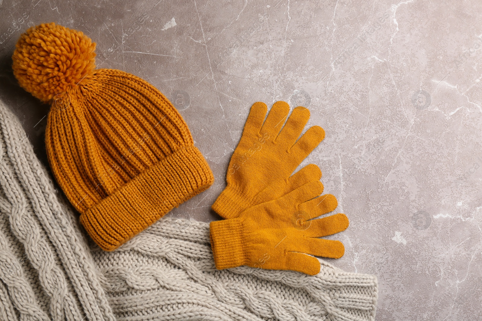 Photo of Stylish gloves, scarf and hat on light grey marble table, flat lay