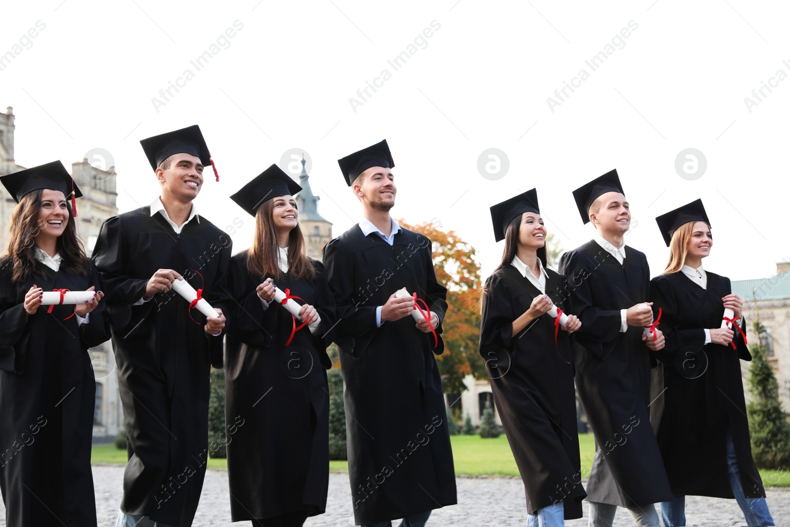 Photo of Happy students with diplomas outdoors. Graduation ceremony