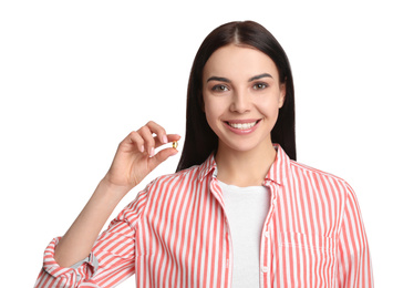 Young woman with vitamin capsule on white background