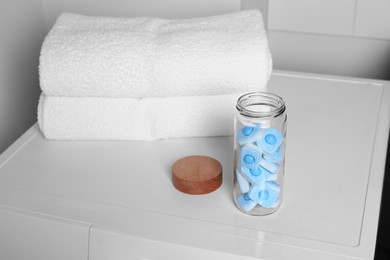 Photo of Glass jar with water softener tablets on washing machine in bathroom