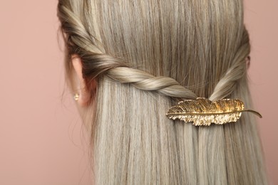 Young woman with beautiful gold hair clip on pink background, closeup