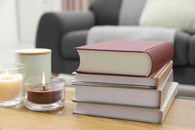 Books and burning candles on wooden table indoors