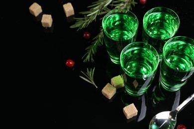Absinthe in shot glasses, cranberries, rosemary and brown sugar on mirror table, space for text. Alcoholic drink