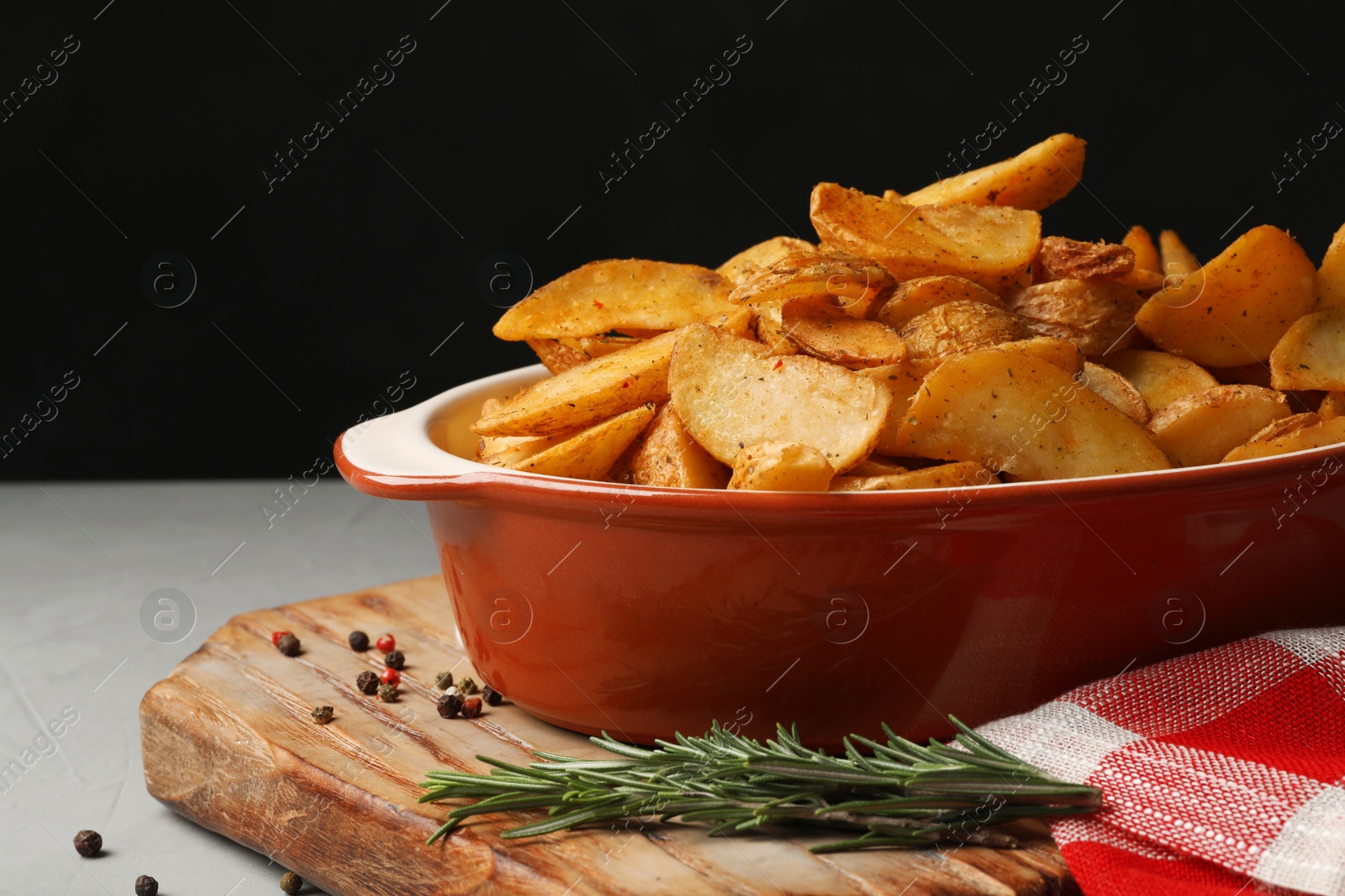 Photo of Dish of delicious oven baked potatoes on table, closeup