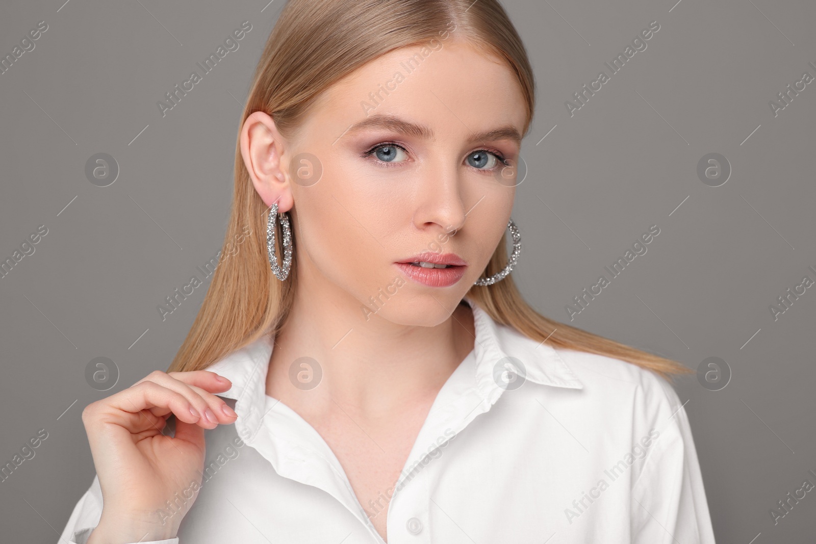 Photo of Beautiful young woman with elegant earrings on gray background