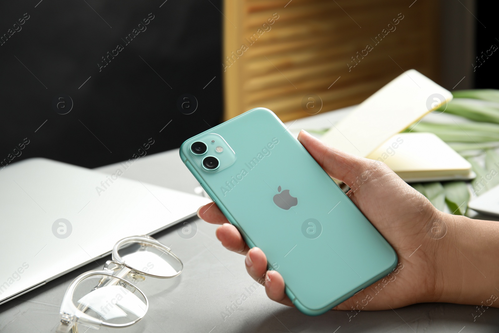 Photo of MYKOLAIV, UKRAINE - JULY 9, 2020: Woman holding Iphone 11 Green at table, closeup