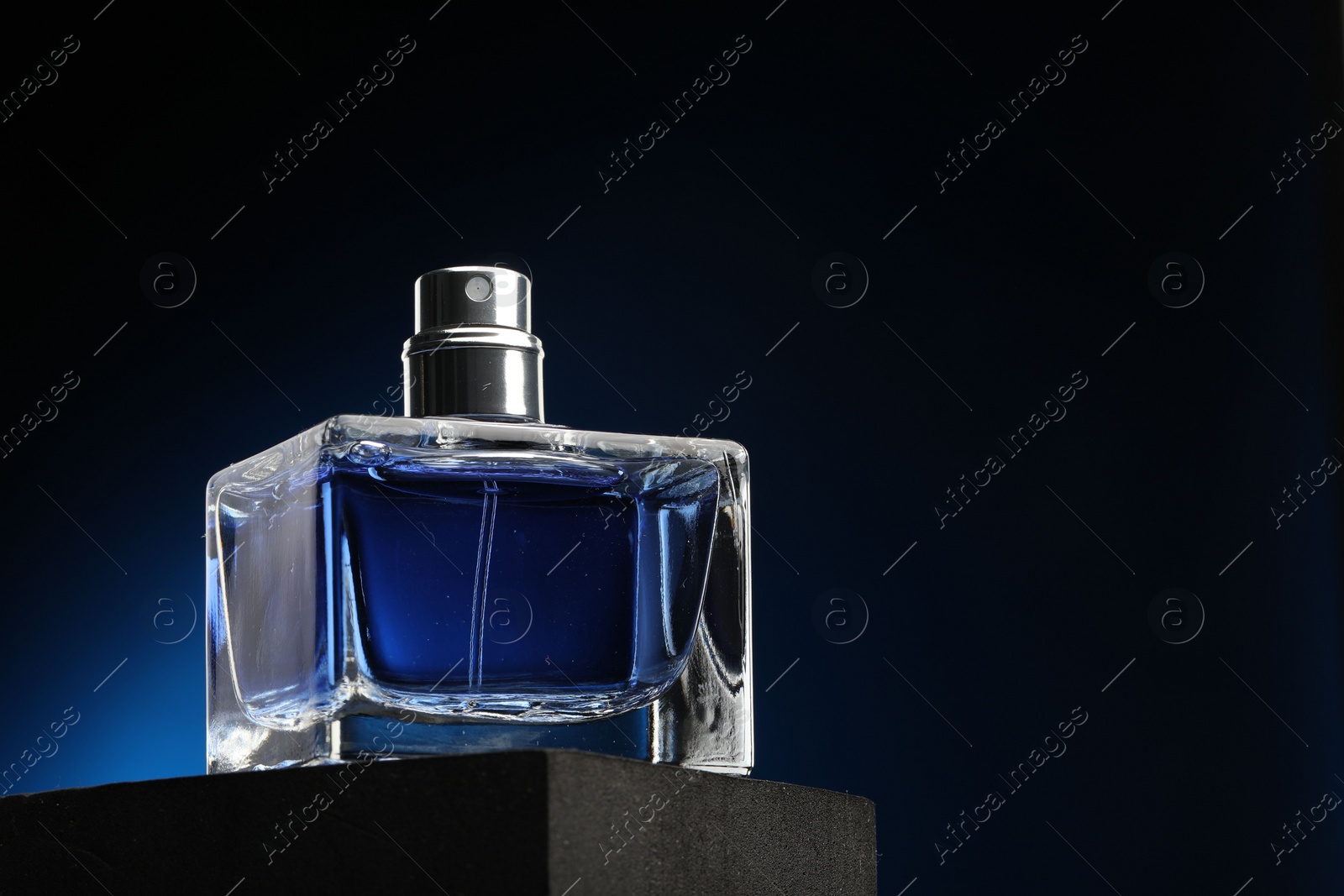 Photo of Luxury men`s perfume in bottle against dark background, low angle view. Space for text