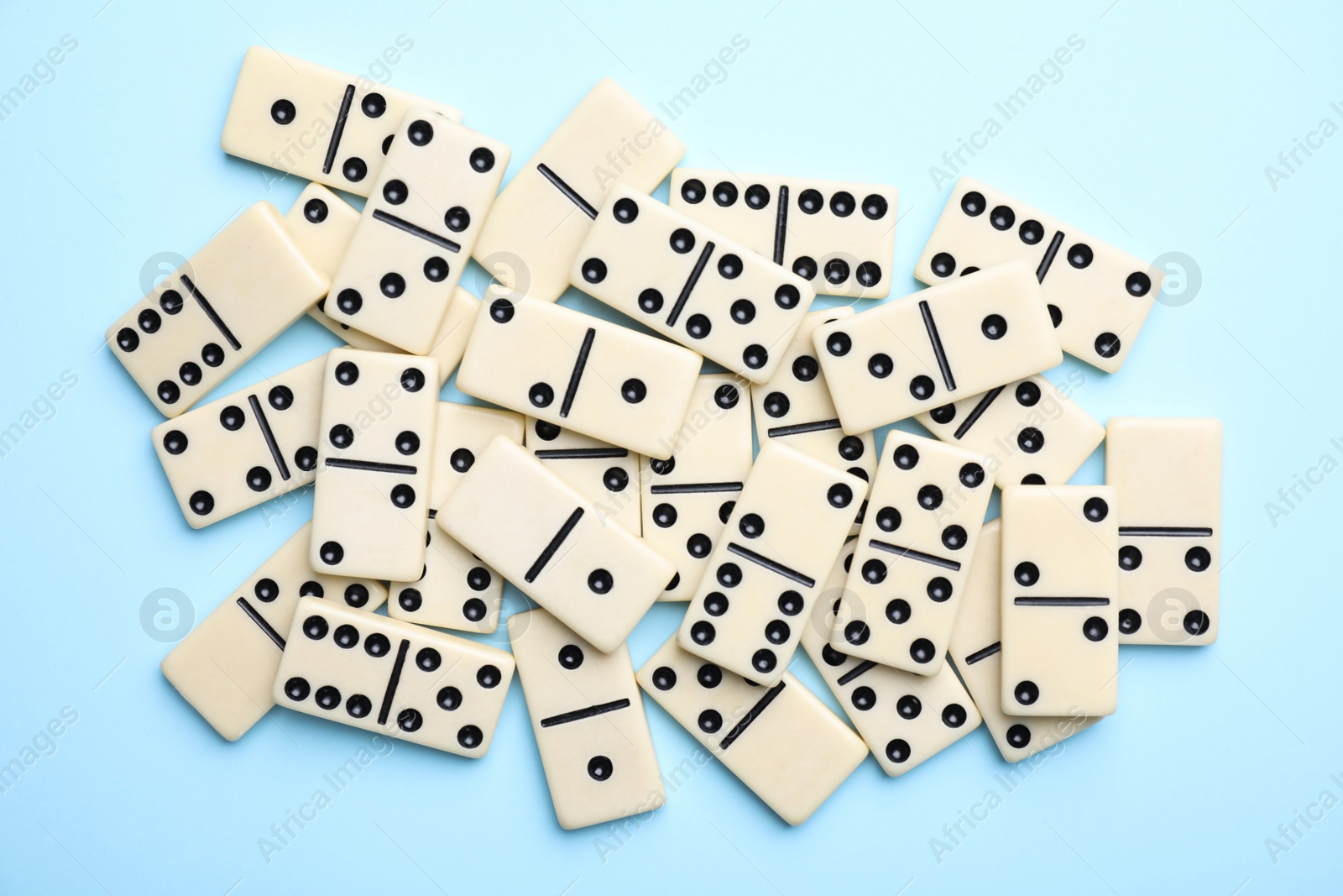 Photo of Classic domino tiles on light blue background, flat lay