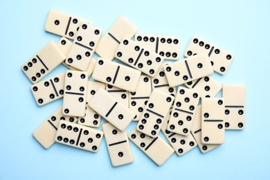 Classic domino tiles on light blue background, flat lay