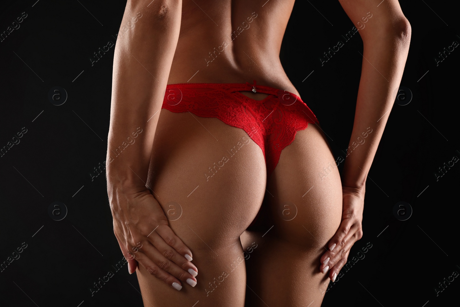 Photo of Woman in red sexy panties on black background, closeup