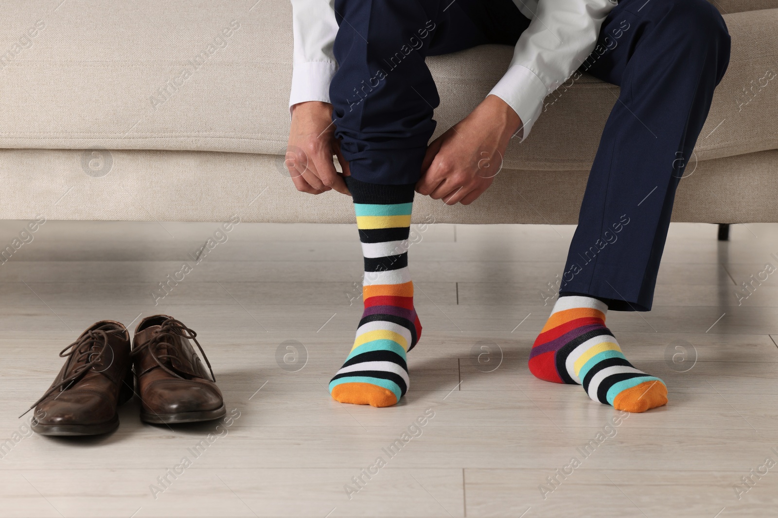 Photo of Man putting on colorful socks indoors, closeup