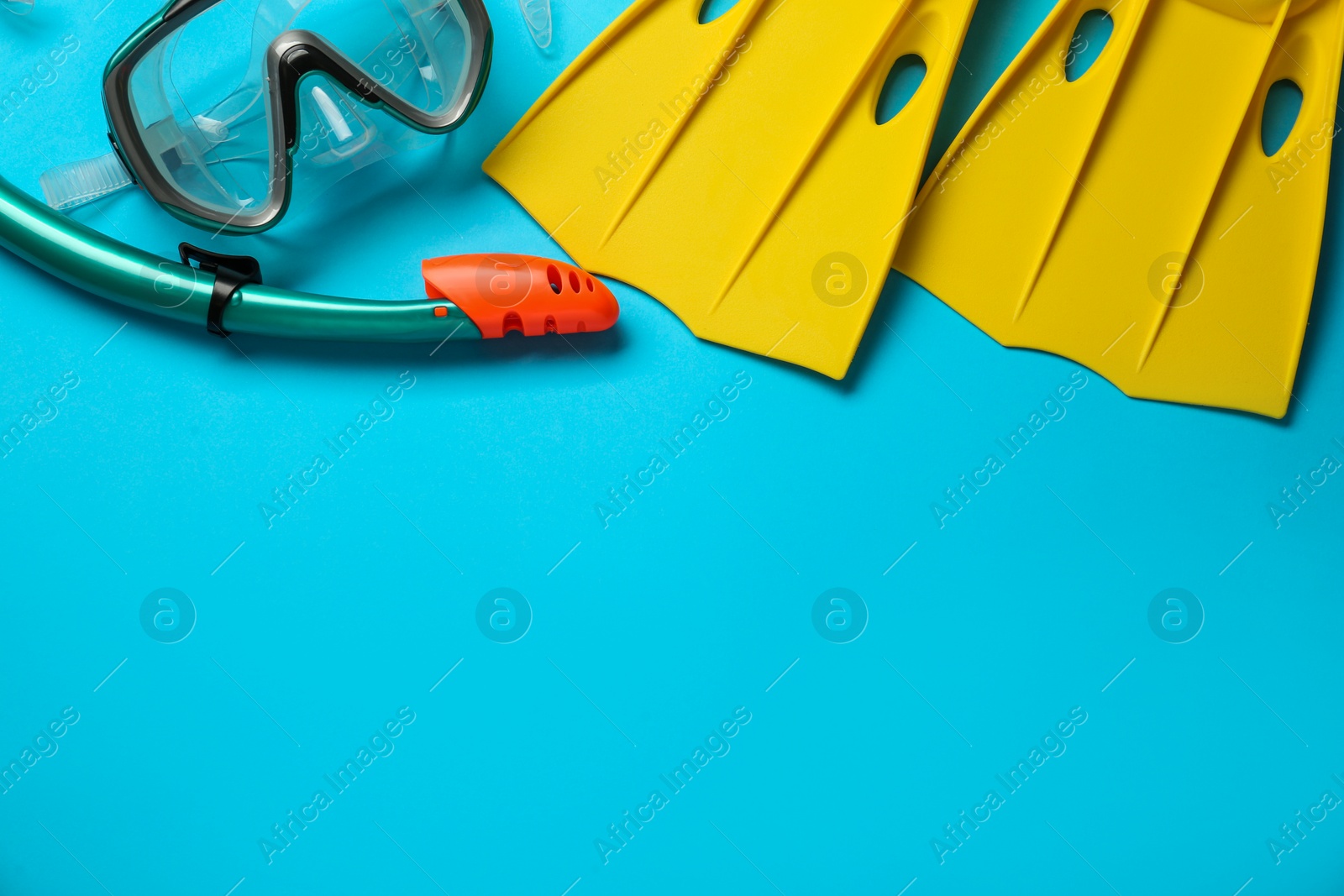 Photo of Pair of yellow flippers and mask on light blue background, flat lay. Space for text