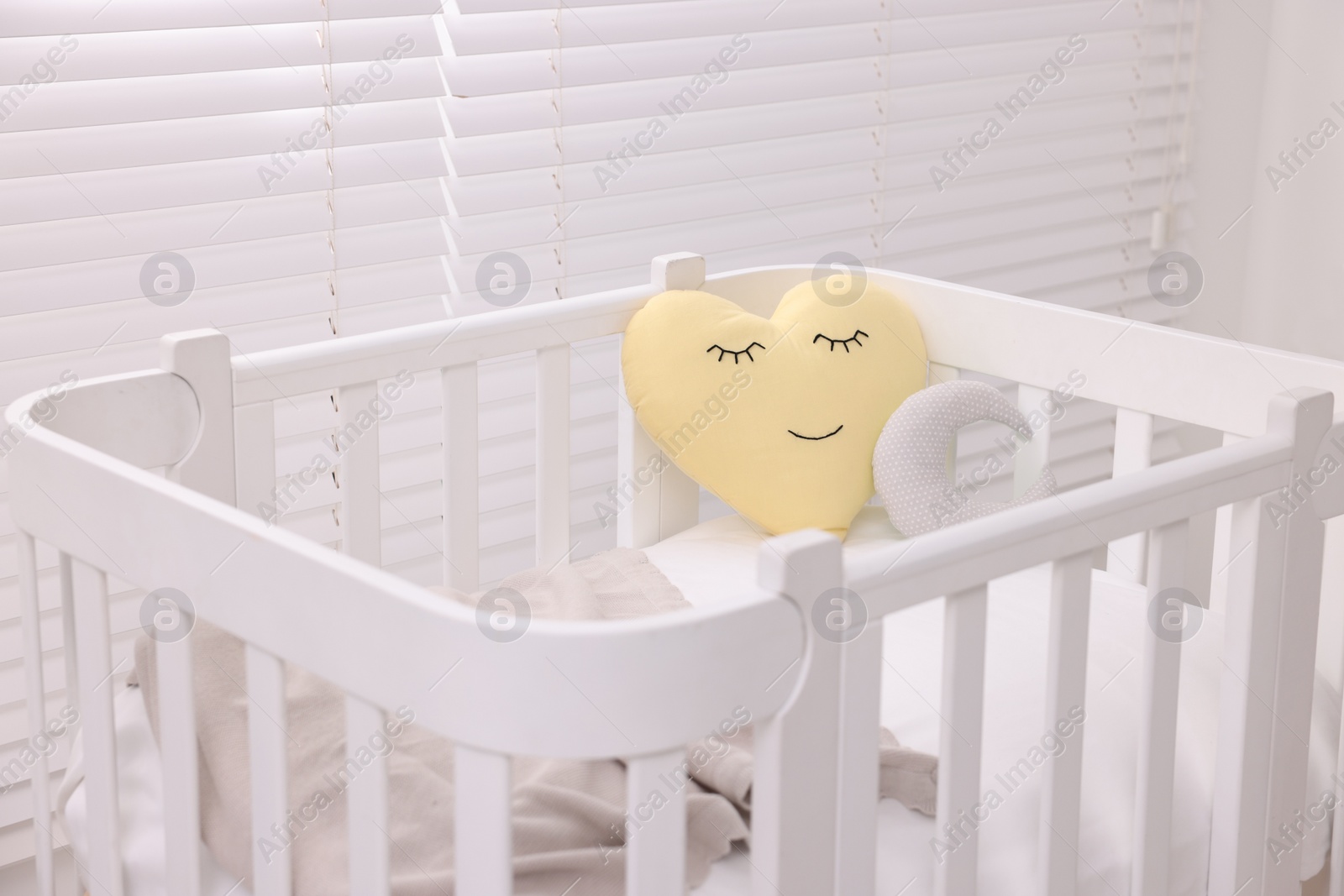 Photo of Comfortable crib with pillows in baby's room, closeup. Interior design