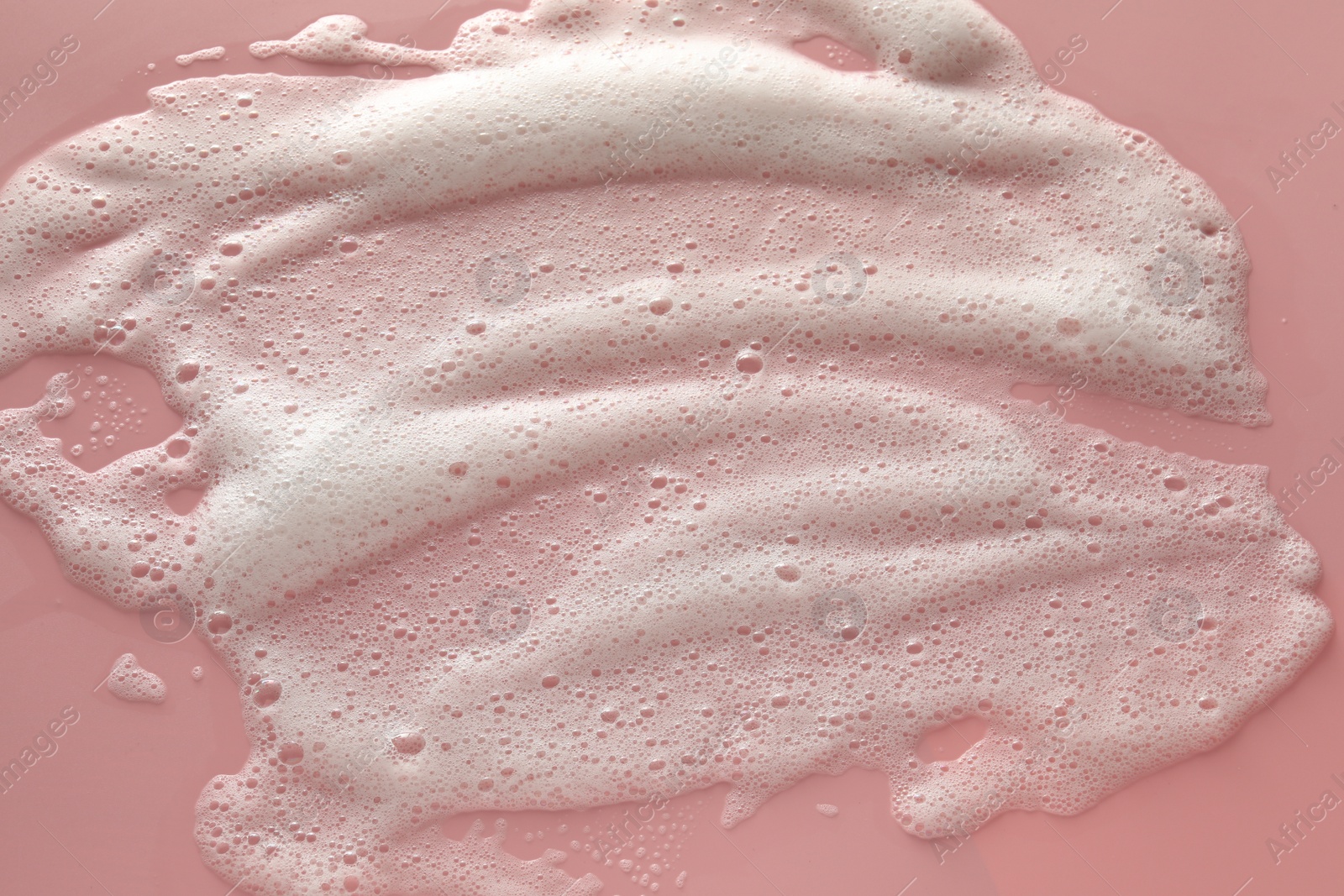 Photo of White washing foam on pale pink background, top view