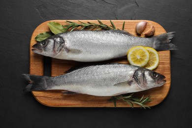 Tasty sea bass fish on black textured table, top view