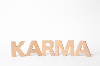 Word Karma made of wooden letters on white background, space for text