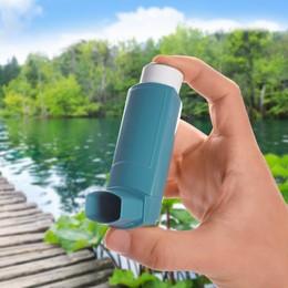 Image of Man with asthma inhaler near lake, closeup. Emergency first aid during outdoor recreation