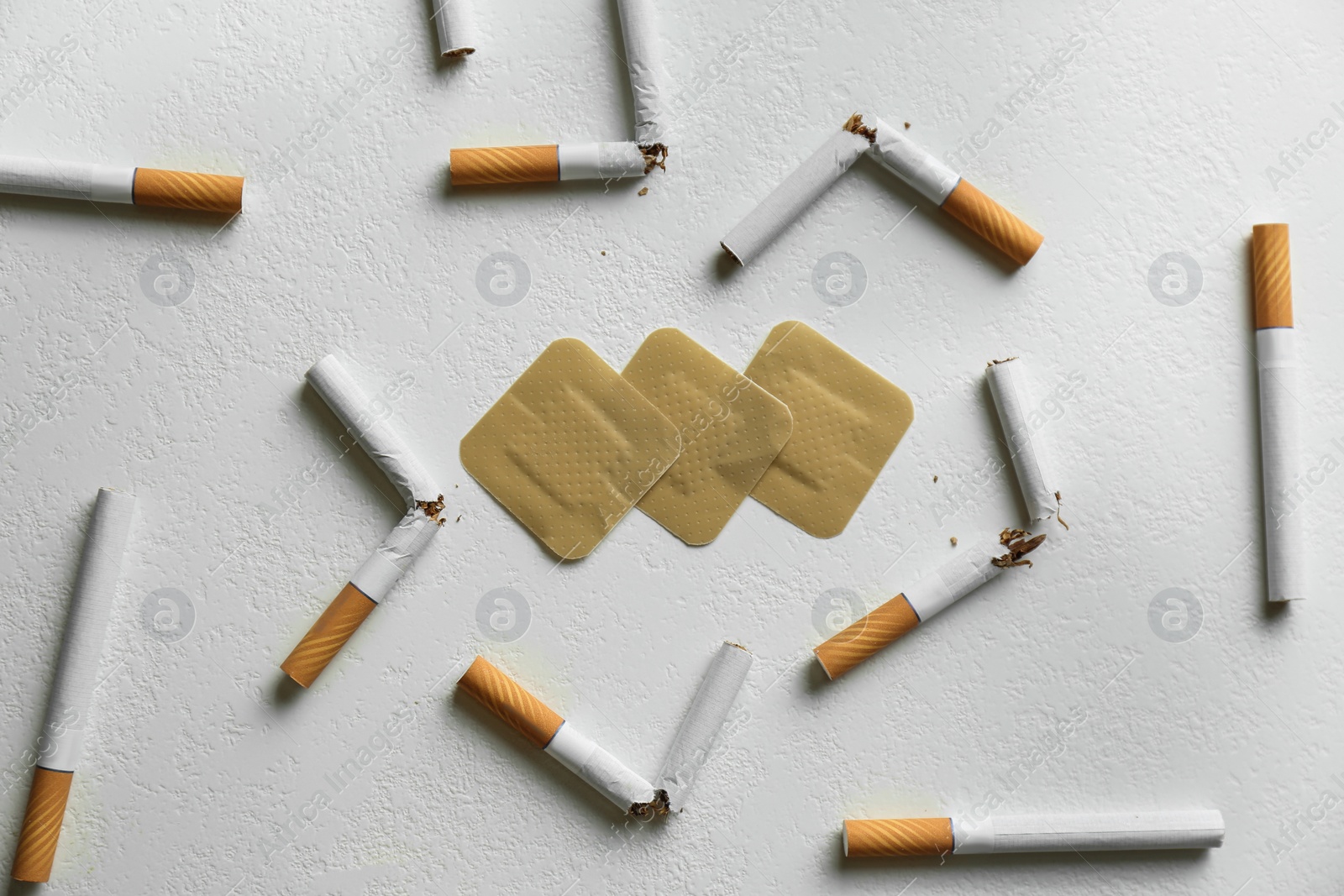 Photo of Nicotine patches and broken cigarettes on white background, flat lay