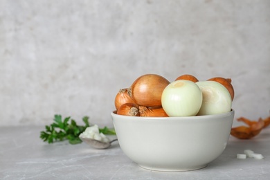 Bowl with fresh ripe onions on table