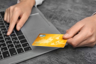 Woman with credit card using laptop at table