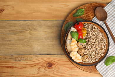 Tasty buckwheat porridge with meat and mushrooms on wooden table, flat lay. Space for text