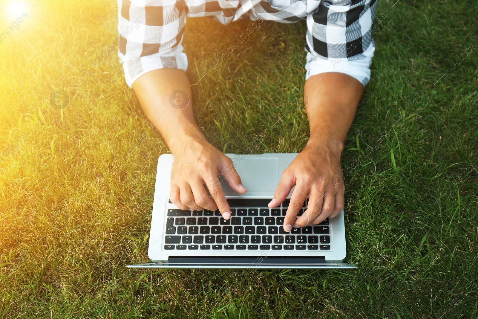 Image of Man working with laptop outdoors on sunny day, closeup